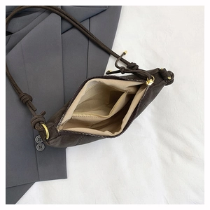 Detail of dark brown dumpling bag showing interior lining and gold hardware knot