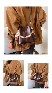 Detail of deep brown bucket bag with gold chain and silk scarf on strap