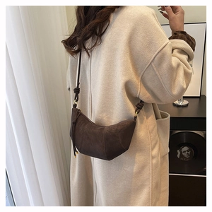 Detail of a dark brown suede crescent bag with knotted shoulder strap on a model back