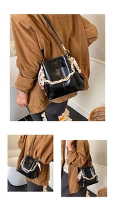 Detail of black glossy leather bucket bag with gold chain and printed silk scarf accessory