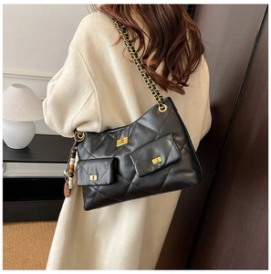 Close-up of quilted black shoulder bag featuring gold twist locks and chain strap detail