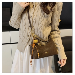 Close-up of brown suede dumpling bag with tassel, wooden beads and yellow fuzzy charm