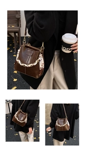 Detail of dark brown bucket bag with cherry print scarf and gold chain on asphalt