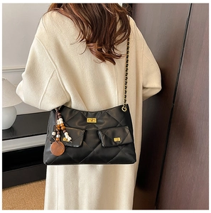 Detail of black quilted shoulder bag with gold chain strap and boho bead charm