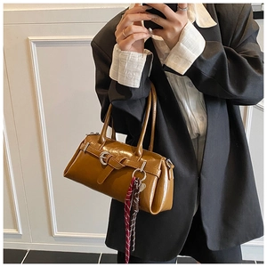 Close-up of caramel leather baguette bag with metal buckle and checkered silk scarf detail