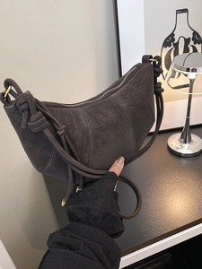 Minimalist dark grey suede crescent bag with knot detail and golden zipper closure