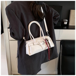Detail of cream white PU leather pillow bag featuring silver hardware and a woven tassel charm