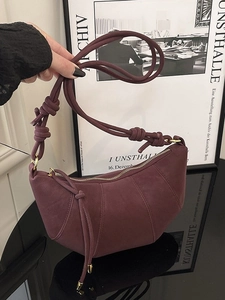 Burgundy faux suede crescent shoulder bag with knotted strap and gold hardware accents