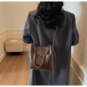 Detail view of a vintage dark brown tote bag showing its smooth texture and stylish strap