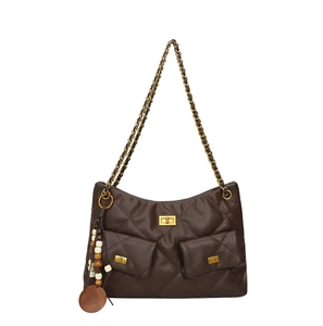 Detail of dark brown quilted shoulder bag with gold turn-locks and chain strap