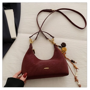 Detailansicht einer burgunderroten Hobo-Tasche mit ethnischen Holzperlen und Quasten