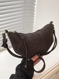 Dark brown faux suede croissant bag with minimalist curved design and gold hardware