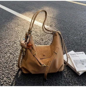 Sac demi-lune en cuir marron avec breloque ours sous une lumière naturelle