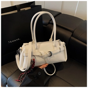Detail of white leather baguette bag with decorative buckle and contrast woven charm