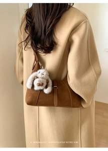 Deep brown suede shoulder bag with buckle detail and white plush rabbit charm