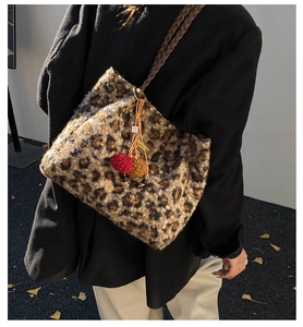 Detail of plush leopard print tote bag with woven strap and colorful pompom accessories