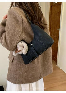 Black suede shoulder bag with minimalist stitching and gray plush bunny charm detail
