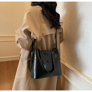 Detail of glossy black leather handbag with magnetic buckle and fashion texture