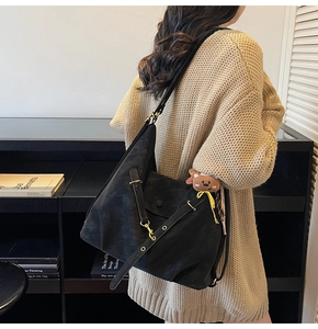 Detail of black suede tote bag with magnetic flap pocket and golden metal hardware accent
