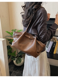 Sac cabas plissé marron avec texture cuir vintage porté à l'épaule dans un bureau