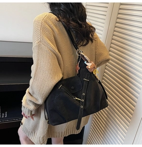 Détail d'un grand sac cabas vintage en daim noir avec bretelles et breloque petit ourson