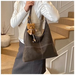 Detailed view of the dark brown matte tote bag with cross-stitch design and plush bear charm