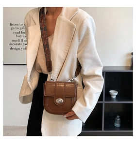 Detail of vintage brown saddle bag with ethnic pattern wide strap and silver clasp