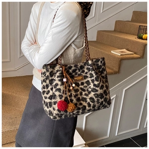 Detail of plush leopard print tote bag featuring woven leather handles and soft faux fur texture