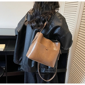 Detail view of a vintage brown bucket bag with tassel and textured leather finish