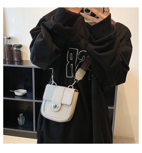 Detail of cream saddle bag with silver twist lock and geometric woven shoulder strap