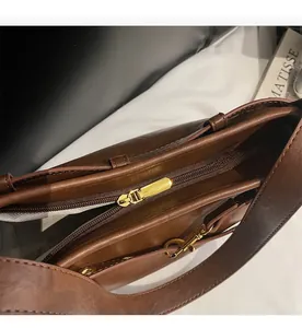 Détails de la fermeture éclair dorée lisse et de la doublure sur le sac en cuir marron