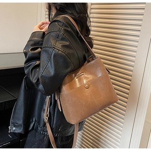 Close-up of brown leather bucket bag with front pocket and adjustable shoulder strap