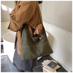 Detail of olive green hobo bag with contrast white stitching and cute bear charm