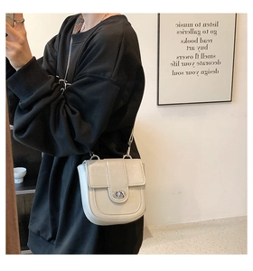 Chic off-white saddle bag with silver twist lock and leather strap shown on a model
