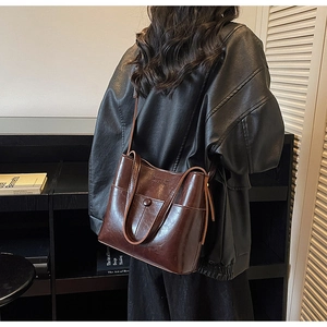 Detail of dark brown waxed leather tote bag with metallic snap and premium glossy finish