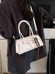 Glossy white faux leather Boston bag with belt buckle and red braided strap charm