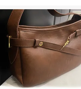 Vue macro d'un sac à bandoulière vintage marron foncé avec boucles métalliques dorées