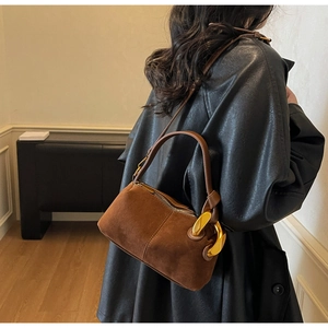 Detail of a brown suede Boston bag with gold buckle hardware and leather strap