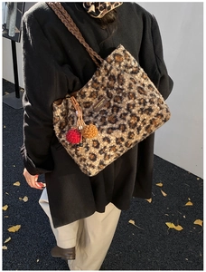 Detail view of leopard print plush tote bag with woven strap and colorful pompom accents