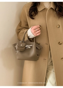 Detail of taupe lychee texture leather handbag with silver buckle and mini pouch