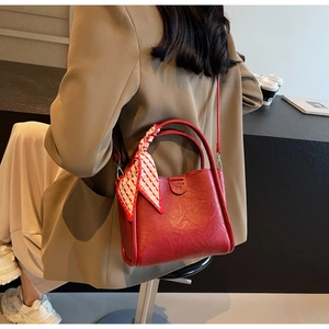 Detail of red leather bucket bag with silk scarf handle and embossed fashion logo