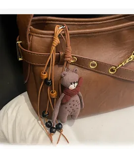 Détail du sac en cuir marron avec breloque ours en tricot et perles en bois