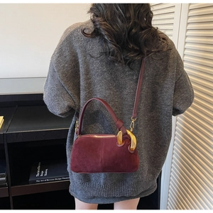 Detail of burgundy suede Boston bag with gold ring hardware and detachable shoulder strap
