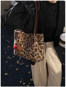 Detail of leopard print plush tote bag with woven strap and decorative pompom charm