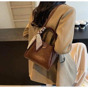 Dark brown leather bucket bag with silk scarf detail shown on model from side view