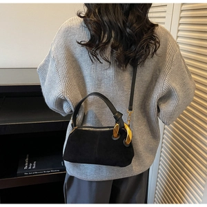 Detail of a black suede Boston bag with a stylish chunky gold chain and slim shoulder strap