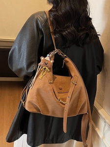 Sac hobo vintage en cuir marron avec pendentif ours porté par un mannequin en veste