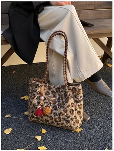 Detail of leopard print plush tote with woven handle and furry charm in autumn setting
