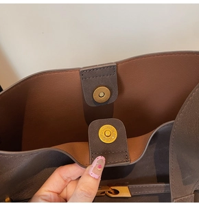 Detailed macro shot of the magnetic metal buckle and fine stitching on the tote bag