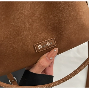 Detail of brown litchi pattern leather bag with BopinJue logo and fine stitching